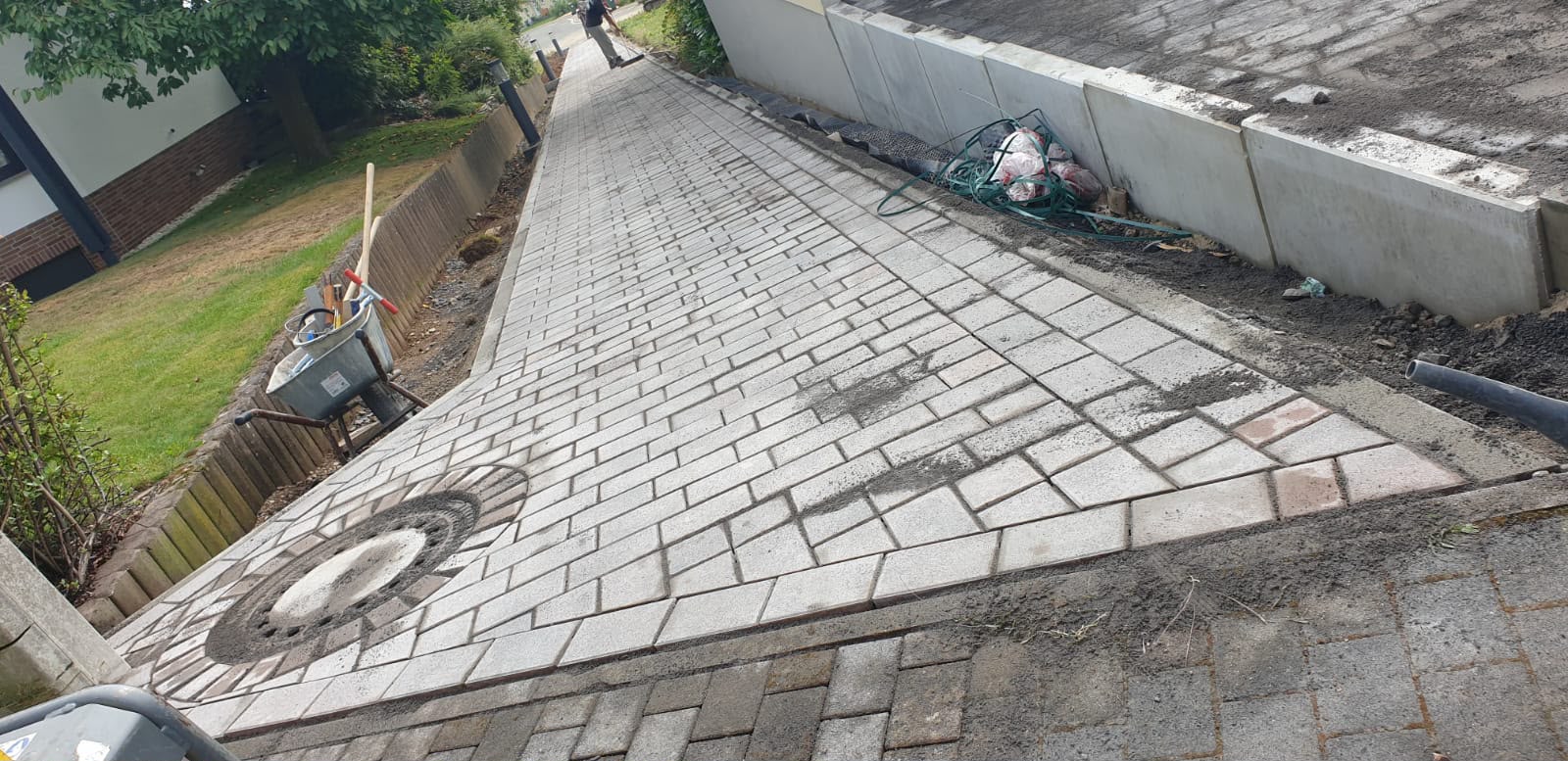 Gepflasterter Weg mit Mosaikkreis und Natursteinmauer