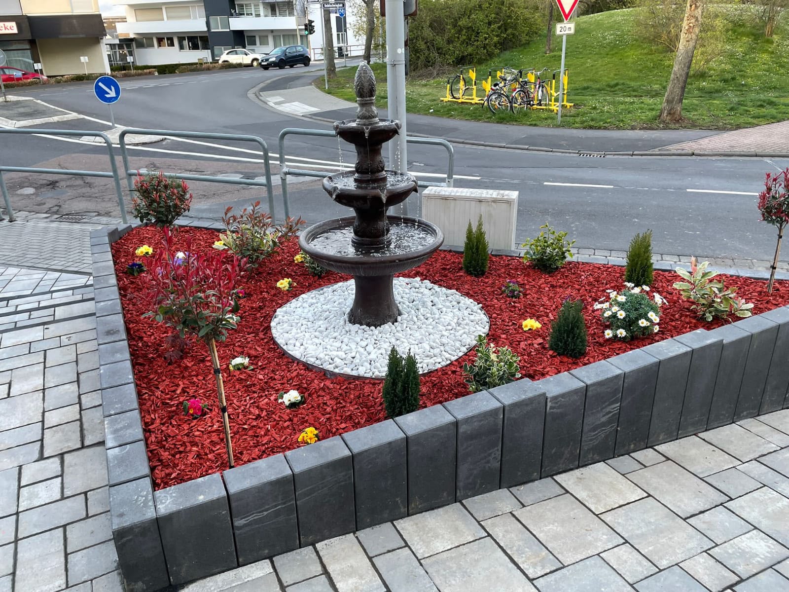 Gestaltetes Beet mit Brunnen und rotem Mulch